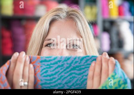 Porträt einer erwachsenen Frau, die ihr Gesicht mit einem Schal in einem Café in Bayern versteckt Stockfoto