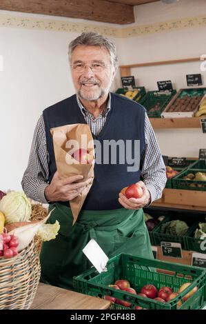 Porträt eines leitenden Ladenbesitzers, der Äpfel im Laden in Bayern verkauft Stockfoto