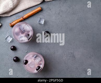 Brasilianischer jabuticaba Caipirinha in Gläsern mit Eis und Früchten auf Steinhintergrund mit Kopierbereich. Stockfoto