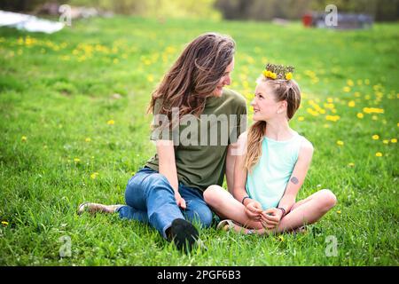 Mutter und Tochter sitzen zusammen auf einer Löwenwiebelwiese. Stockfoto