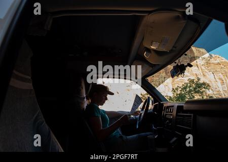 Junge Frau im Van, die die Karte des Zion-Nationalparks in Utah liest Stockfoto