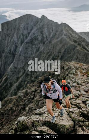 Eine Wanderin führt die Begleiterin entlang der Knife Edge auf Maine's Katahdin Stockfoto