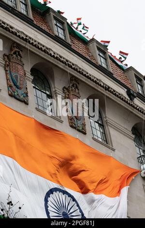 London, Großbritannien. 22. März 2023. Vor der Hohen Kommission hängt eine riesige indische Flagge, wobei Mitarbeiter beobachten, wie Sikhs unten gegen Rechtsverletzungen in Pu protestieren Stockfoto