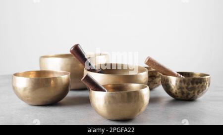 Eine Gruppe tibetischer Gesangsschüsseln mit Stöcken auf einem grauen Steintisch Stockfoto