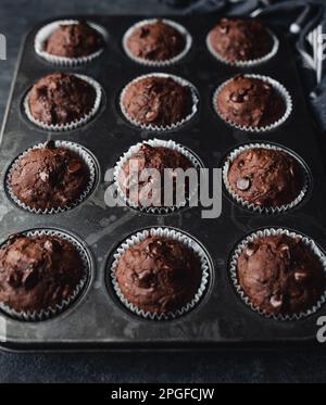 Nahaufnahme der Dose mit Schokoladenzucchini-Muffins auf schwarzem Hintergrund. Stockfoto