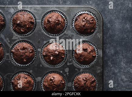 Über dem Kopf eine Dose Schokoladenzucchini-Muffins auf schwarzem Hintergrund. Stockfoto