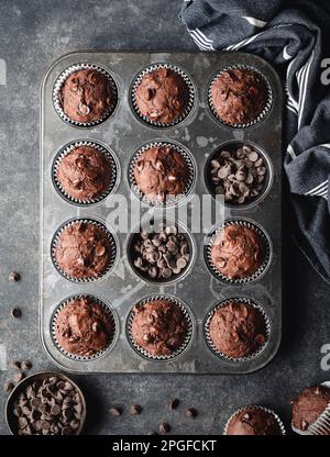 Über dem Kopf eine Dose Schokoladenzucchini-Muffins auf schwarzem Hintergrund. Stockfoto