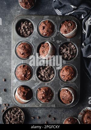 Über dem Kopf eine Dose Schokoladenzucchini-Muffins auf schwarzem Hintergrund. Stockfoto