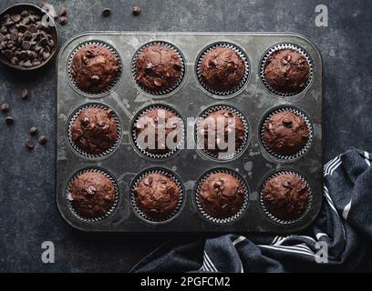 Über dem Kopf eine Dose Schokoladenzucchini-Muffins auf schwarzem Hintergrund. Stockfoto