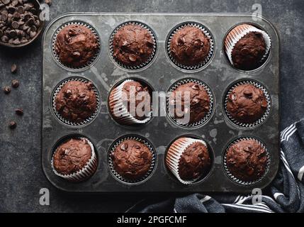 Über dem Kopf eine Dose Schokoladenzucchini-Muffins auf schwarzem Hintergrund. Stockfoto