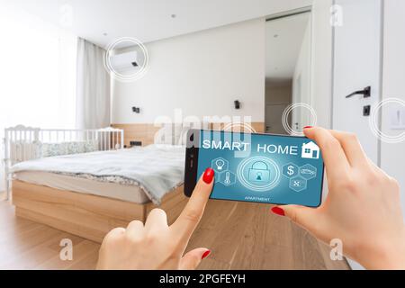 Nahaufnahme Smartphone in weiblicher Hand mit Smart-Home-System-App-Schnittstelle auf Handybildschirm, junge Frau, die alle Systeme des Hauses per Telefon steuert Stockfoto