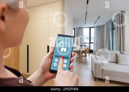 Nahaufnahme Smartphone in weiblicher Hand mit Smart-Home-System-App-Schnittstelle auf Handybildschirm, junge Frau, die alle Systeme des Hauses per Telefon steuert Stockfoto