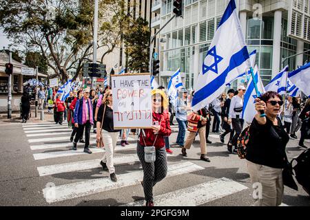 Tel Aviv, Israel. 22. März 2023. Eine Frau hält ein Plakat, wenn sie während eines Protests gegen die Justizreform die Straße überquert. In Jerusalem und Tel Aviv fanden Proteste gegen die Justizreform der Regierung statt, wobei mehrere Regierungsminister ins Visier genommen wurden, als die Koalition ihre umstrittenen Pläne vorantreibt. (Foto: Eyal Warshavsky/SOPA Images/Sipa USA) Guthaben: SIPA USA/Alamy Live News Stockfoto