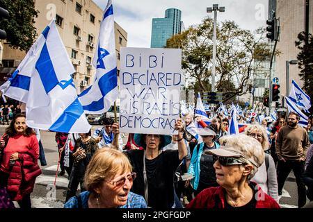 Tel Aviv, Israel. 22. März 2023. Eine Frau hält ein Plakat, wenn sie während eines Protests gegen die Justizreform die Straße überquert. In Jerusalem und Tel Aviv fanden Proteste gegen die Justizreform der Regierung statt, wobei mehrere Regierungsminister ins Visier genommen wurden, als die Koalition ihre umstrittenen Pläne vorantreibt. (Foto: Eyal Warshavsky/SOPA Images/Sipa USA) Guthaben: SIPA USA/Alamy Live News Stockfoto