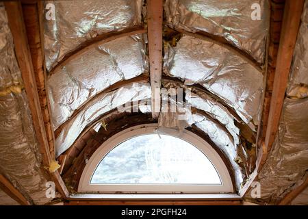 Freiliegende alte Dachdämmung in einem Haus und einem Fenster Stockfoto