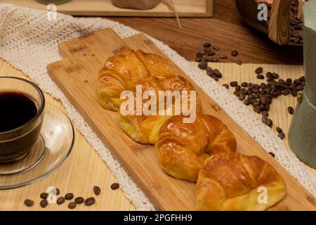 Argentinisches Frühstück. Croissants mit einer Tasse Kaffee und Kaffeebohnen auf Stillleben. Stockfoto
