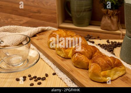 Argentinisches Frühstück. Croissants mit Kaffeekanne, Tasse und Kaffeebohnen im Stillen Stockfoto