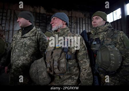 Bakhmut, Ukraine. 22. März 2023. Ukrainische Soldaten hören zu, wie Präsident Wolodymyr Zelenskyy während eines Besuchs an den Frontpositionen in der Donezk-Region am 22. März 2023 in Bakhmut, Ukraine, Bemerkungen vorträgt. Zelenskyy hat die Moral erhöht und den Soldaten, die sich gegen die russische Invasion verteidigen, staatliche Medaillen verliehen. Kredit: Pool Photo/Pressestelle Des Ukrainischen Präsidenten/Alamy Live News Stockfoto