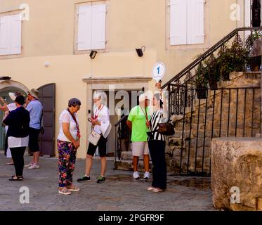 Touristen in Budva, Montenegro. Der Reiseleiter bittet sie, sich um sie zu versammeln. Stockfoto