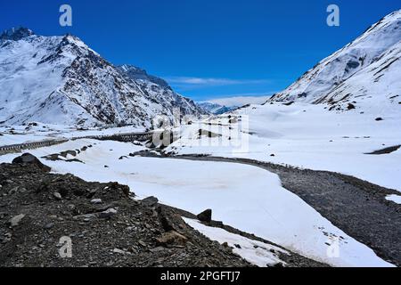 Starke Schneeausbreitung zwischen Felsen am Ufer des Flusses Stockfoto