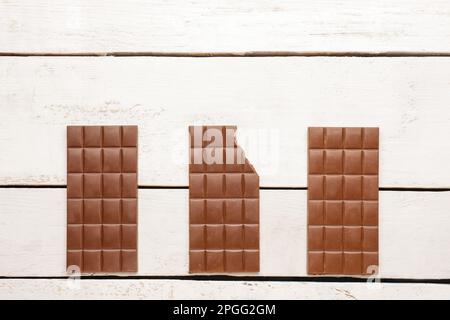 Leckere Schokoladenstücke auf hellem Holzhintergrund Stockfoto