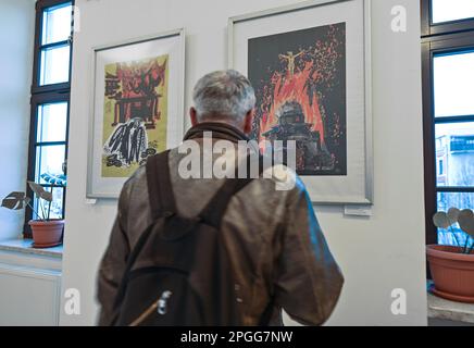 KRAKAU, POLEN - 22. MÄRZ 2023: Ein Besucher sieht die Werke von Inna Linyova auf der Posterausstellung „Save the Future“, die am 22. März 2023 in der Provinzbibliothek in Krakau, Polen, eröffnet wurde. Inna Linyova, eine ukrainische Malerin und seit 2003 in den USA ansässige Grafikdesignerin, erstellt avantgardistische Kompositionen. Der Schmerz der Künstlerin für die Situation ihrer Heimat während des Krieges spiegelt sich in ihrer Arbeit wider, indem sie die Sprache der Plakate benutzt, um die Aufmerksamkeit auf den Albtraum zu lenken, der aus Russland in die Ukraine kam. Auf einem ihrer Plakate, "Schwangere Ukraine", wird die Heimat als eine schwangere Frau als Protektin dargestellt Stockfoto