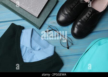 Stilvolle Schuluniform für Jungen, Brillen, Bücher und Rucksack auf hellblauem Holzhintergrund, flach liegend Stockfoto