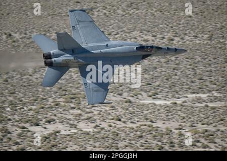 Lone Pine, CA - 10. November 2022: Navy F-18 Fighter Jet fliegt schnell auf der niedrigen Ebene von Sidewinder-D. Stockfoto