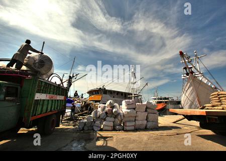 Eine Szene, die Fracht, Lastwagen, traditionelle pinisi-Schiffe und Arbeiter an einem glühend heißen Tag im Hafen von Paotere in Ujung Tanah, Makassar, South Sulawesi, Indonesien zeigt. Laut dem Bericht des Weltklimarates (Intergovernmental Panel on Climate Change, IPCC) aus dem Jahr 2023 mit dem Titel „Climate Change 2022: Impacts, Adaptation and Vulnerability“ (Klimaänderung: Auswirkungen, Anpassung und Verwundbarkeit) werden Arbeitnehmer im Freien zunehmend Hitzestress ausgesetzt und ihre arbeitskapazität verringert. Der Klimawandel wird Outdoor-Arbeitnehmer zunehmend Hitzestress aussetzen und die arbeitskapazität verringern, so der Bericht aus dem Jahr 2023, der von der... Stockfoto