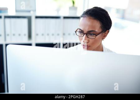 Der Connected Doctor ist ein aktueller Arzt. Eine junge Ärztin, die einen Computer in ihrem Sprechzimmer benutzt. Stockfoto