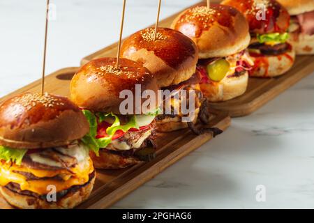 Viele verschiedene Burger mit Zutaten auf einer Holzplatte Stockfoto