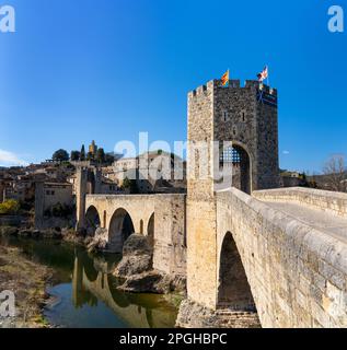 Besalu, Spanien - 1. März 2023: Blick auf die mittelalterliche romanische Brücke und das Dorf Besalu in Katalonien Stockfoto