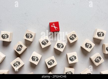 Budgetkürzungskonzept. Einkommenseinbußen, Wirtschaftskrise, Geschäftsdarlehen oder Schulden. Scheren und Geldsymbole auf Holzwürfeln. Stockfoto