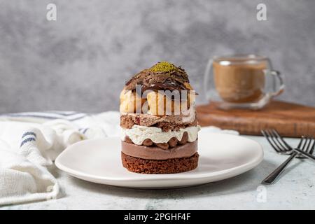 Mehrschichtiger Profiteroles-Kuchen. Schlagsahne, Schokolade und Pistazienkuchen. Stockfoto