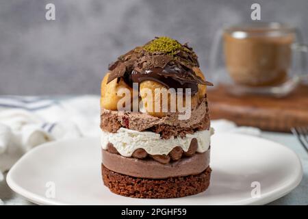 Mehrschichtiger Profiteroles-Kuchen. Schlagsahne, Schokolade und Pistazienkuchen. Schließen. Stockfoto