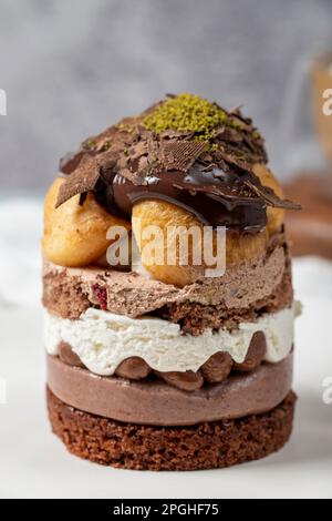 Mehrschichtiger Profiteroles-Kuchen. Schlagsahne, Schokolade und Pistazienkuchen. Schließen. Stockfoto