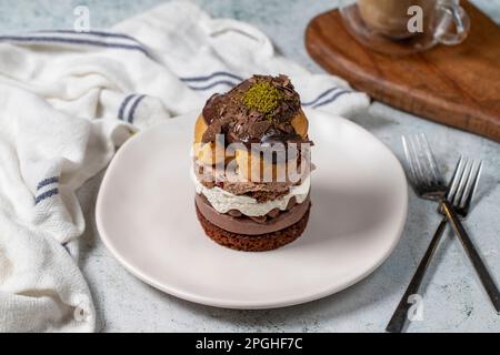 Mehrschichtiger Profiteroles-Kuchen. Schlagsahne, Schokolade und Pistazienkuchen. Stockfoto