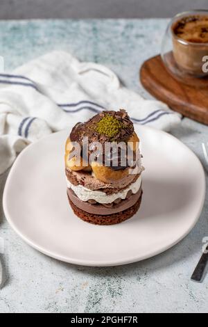 Mehrschichtiger Profiteroles-Kuchen. Schlagsahne, Schokolade und Pistazienkuchen. Stockfoto