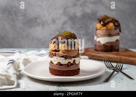 Mehrschichtiger Profiteroles-Kuchen. Schlagsahne, Schokolade und Pistazienkuchen. Stockfoto