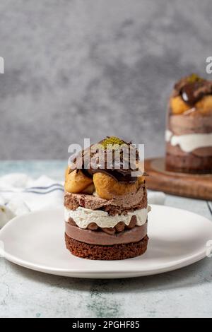 Mehrschichtiger Profiteroles-Kuchen. Schlagsahne, Schokolade und Pistazienkuchen. Stockfoto