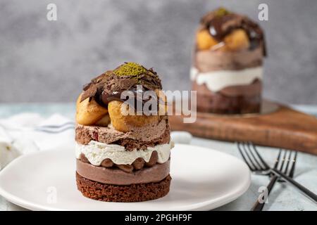 Mehrschichtiger Profiteroles-Kuchen. Schlagsahne, Schokolade und Pistazienkuchen. Schließen. Stockfoto