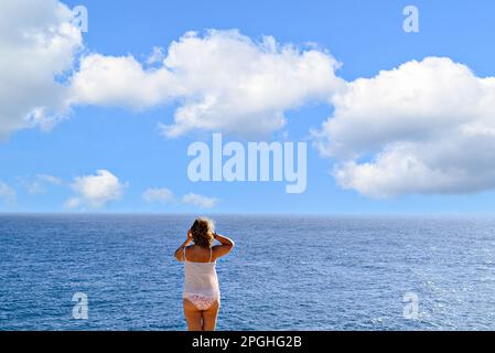 Blonde, lockige Frau im Bikini, die ein Foto mit dem Mobile am Strand am Horizont macht. Barbate, Cadiz Stockfoto