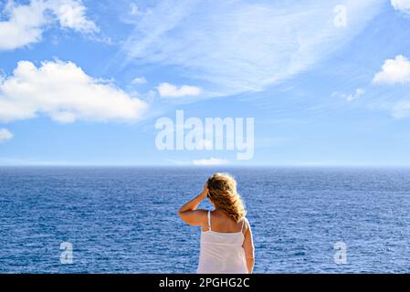 Blonde, lockige Frau im Bikini, die ein Foto mit dem Mobile am Strand am Horizont macht. Barbate, Cadiz Stockfoto