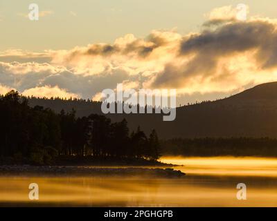 Ein atemberaubender Sonnenuntergang über dem Femunden-See, mit einer ruhigen Reflexion der Gebirgssilhouette in den ruhigen Gewässern und üppigen Wäldern. Stockfoto