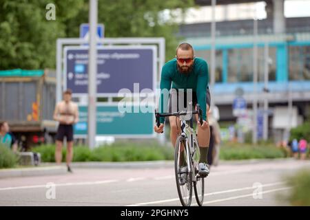 Ein Radfahrer fährt mit dem Fahrrad in einem Stadtpark auf einem Radweg, einem Fahrradhobby, fährt mit dem Fahrrad durch die Stadt, trainiert mit dem Fahrrad. Stockfoto