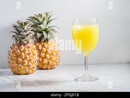Ananassaft in einem Glas auf einem hellen Tisch. Hochwertiges Foto Stockfoto