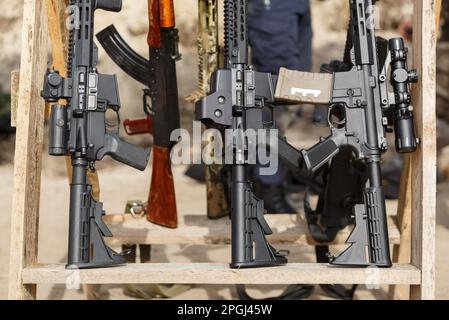 Modernes amerikanisches Sturmgewehr mit Lupen und optischen Oszilloskopen für präzise Schüsse. Karbinen auf einem Waffenstand auf dem Trainingsgelände Stockfoto