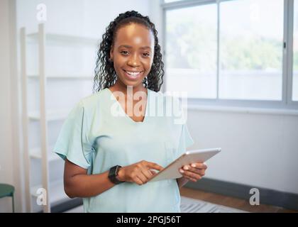 Porträt einer jungen schwarzen Ärztin, lächelnd mit einem digitalen Tablet, eHealth Stockfoto