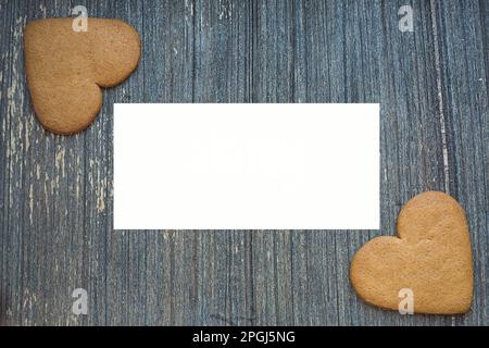 Grauer, gereifter Holzhintergrund mit Ingwerkuchen in zwei Ecken wight copy space in der Mitte. St. Valentinstag-Rahmen. Liebe und Hochzeitseinladungen Stockfoto