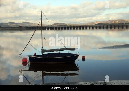 Hölzernes Segelboot und Eisenbahnviadukt, das die Mündung des Flusses Kent von Arnside nach Grange-over-Sands überquert, vom Küstenpfad in der Nähe von Arnside. Stockfoto